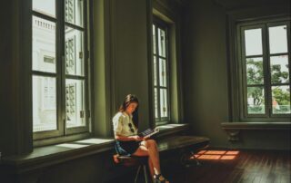 Woman Sitting in Large Room with Windows