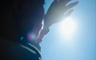 Person Holding Up Hand to Block the Sun