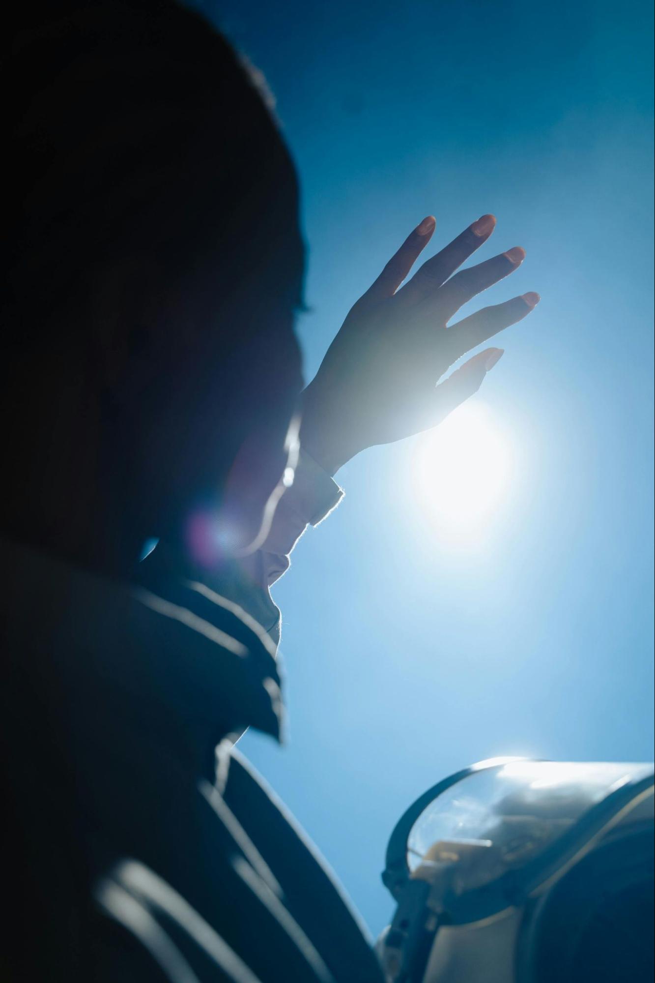 Person Holding Up Hand to Block the Sun