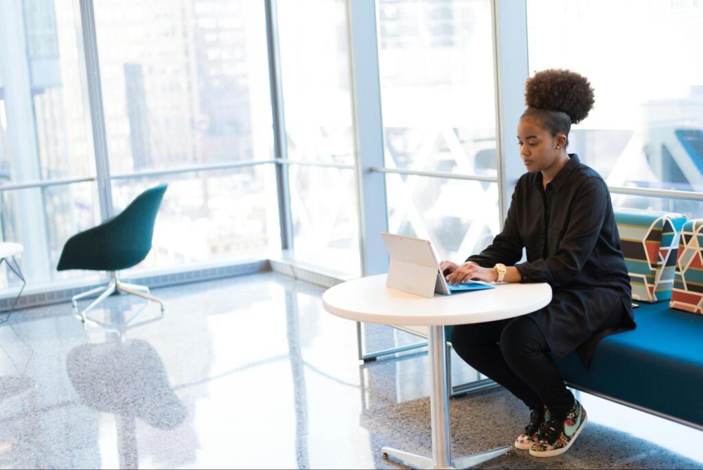 Woman Sitting at Table with iPad and Windows