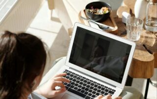 Woman Sitting in a Chair Typing on Laptop