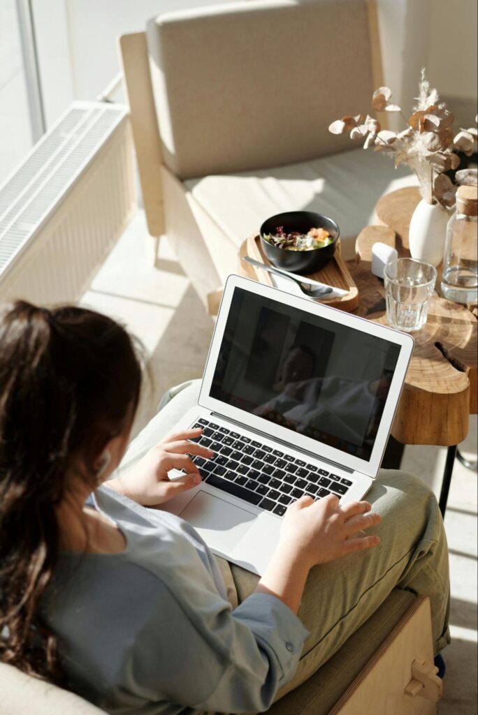 Woman Sitting in a Chair Typing on Laptop