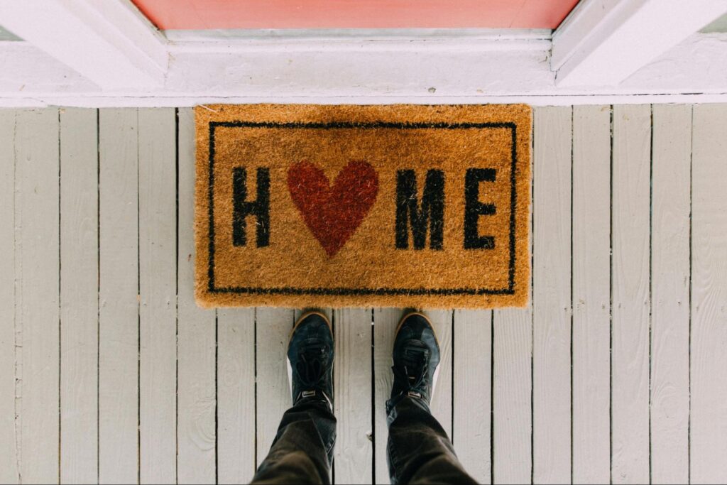 Person Standing at Doorstep with ‘Home’ Doormat
