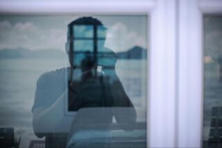 Man in Window Reflection Taking Photo