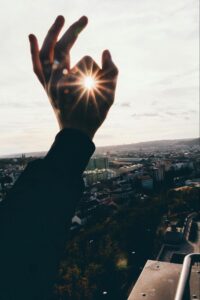 Person Making a Circle with Hand Around the Sun