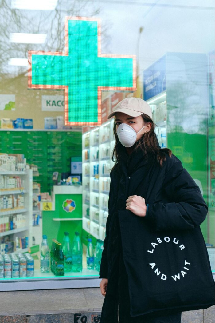 Woman in a Mask in Front of Pharmacy